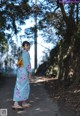 A woman in a kimono standing on a dirt road.