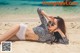 A woman laying on the beach in a bikini and sunglasses.