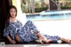 A woman sitting on the ground next to a swimming pool.