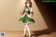 A girl in a green dress and white tights standing on a wooden floor.