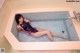 A woman in a bathing suit laying in a bathtub.