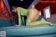 A woman in a green fishnet bodysuit laying on a blue couch.